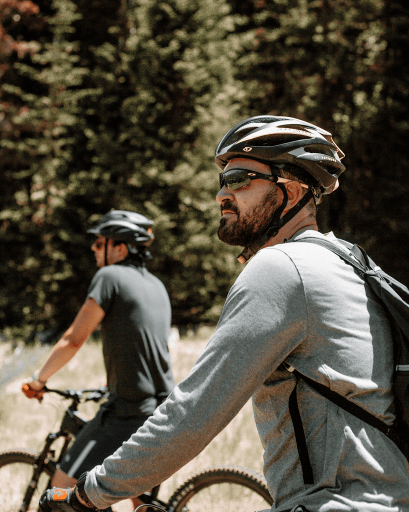 Pessoas pedalando com capacete. Foto de Chris Henry, Unsplash.